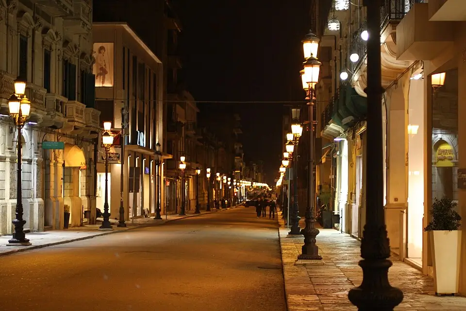 Elegant view of Corso Garibaldi with locals walking among shops and historical buildings in Reggio Calabria
