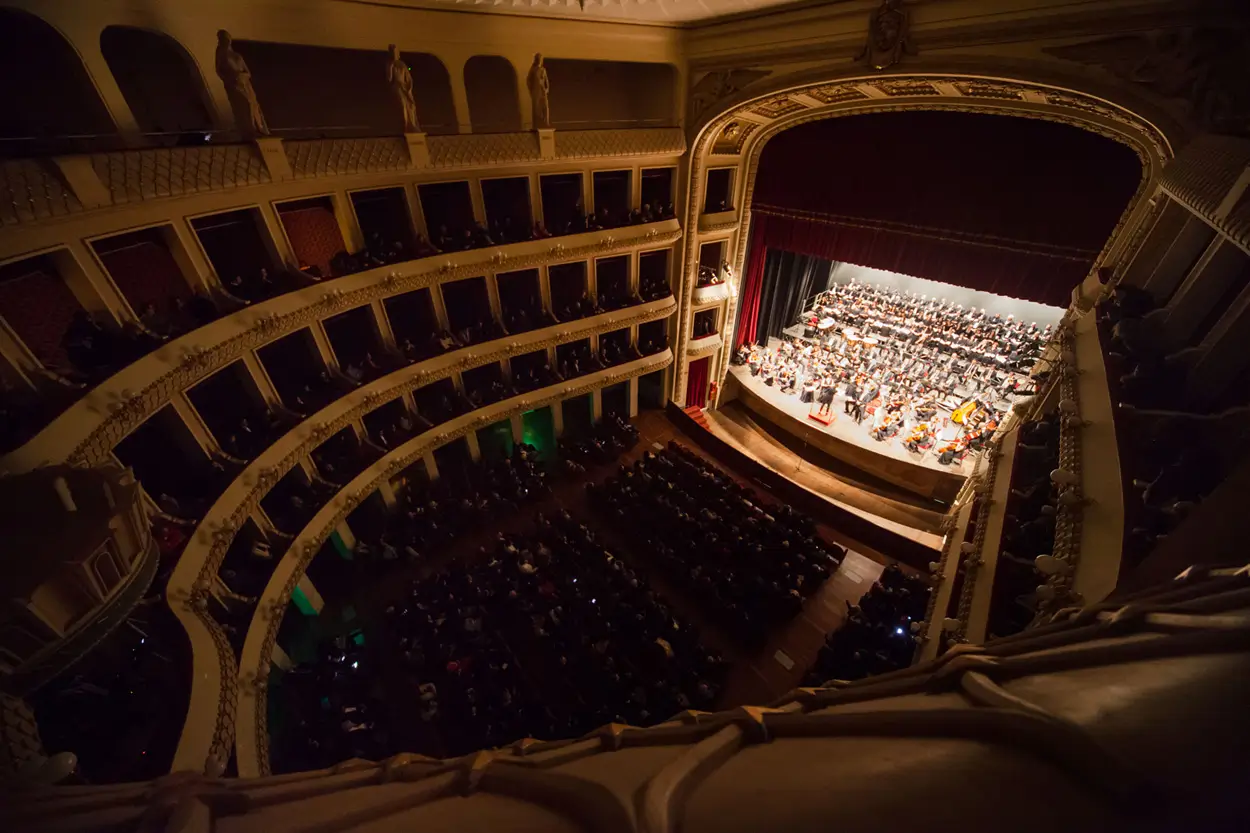 Interior view of Francesco Cilea Theater with red velvet seats and horseshoe-shaped gallery