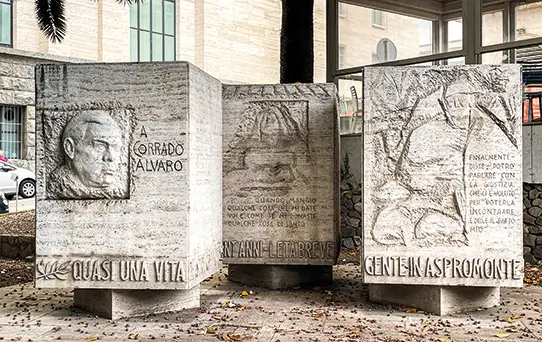 Corrado Alvaro Monument in Reggio Calabria with carved quotes and literary scenes in marble cubes.