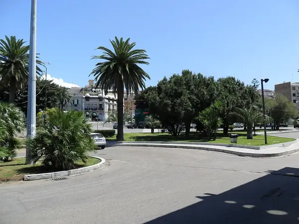 Piazza Indipendenza in Reggio Calabria, with palm trees, scenic roads, and Mount Etna in the distance