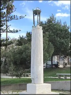 Monument to Diego Vitrioli featuring an ancient marble column with tripod and medallion, set in the cityscape of Reggio Calabria.